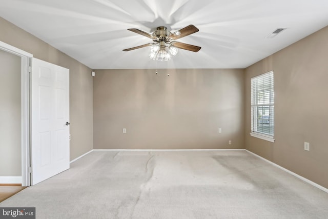carpeted spare room featuring baseboards, visible vents, and ceiling fan