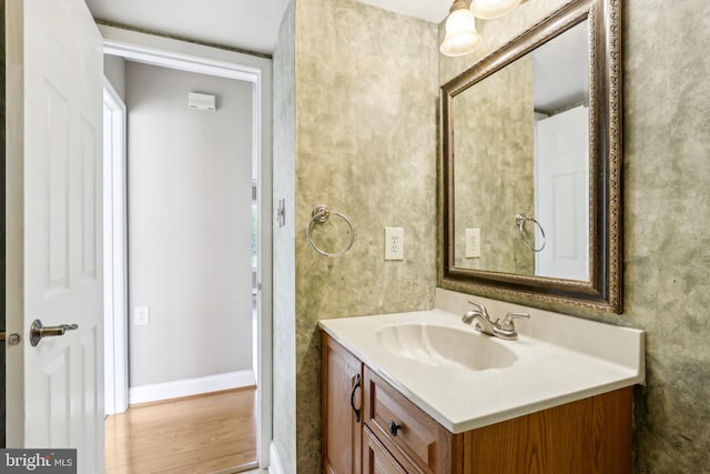 bathroom with wood finished floors, vanity, and baseboards