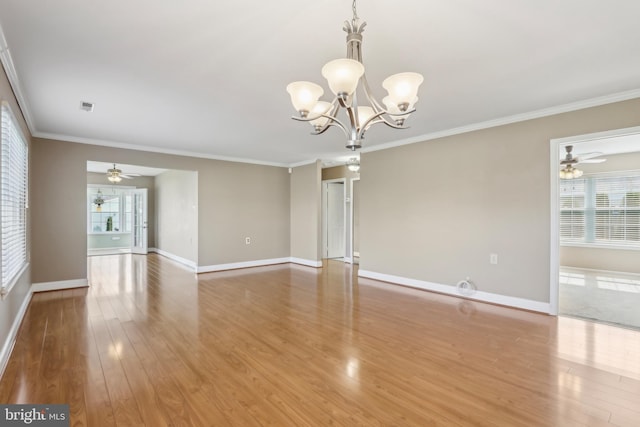spare room featuring crown molding, baseboards, wood finished floors, and plenty of natural light