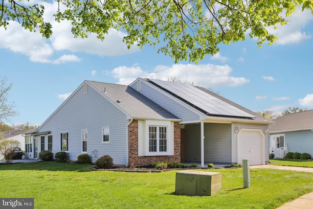 ranch-style house featuring driveway, solar panels, a front lawn, and an attached garage
