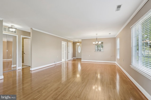 unfurnished living room featuring light wood-style flooring, a chandelier, plenty of natural light, baseboards, and ornamental molding