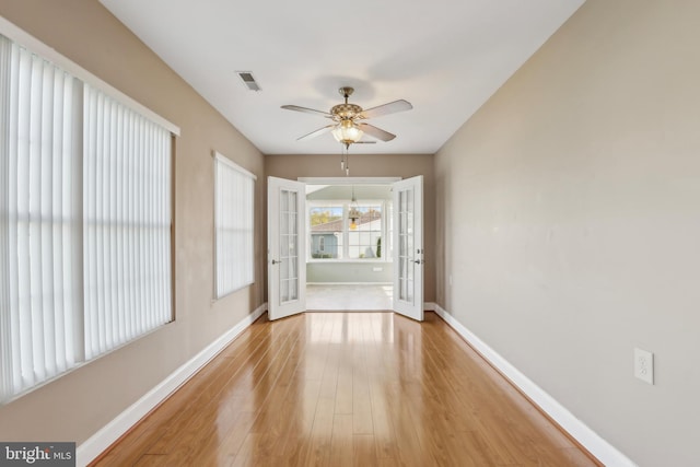 unfurnished room featuring baseboards, visible vents, a ceiling fan, and light wood-style floors