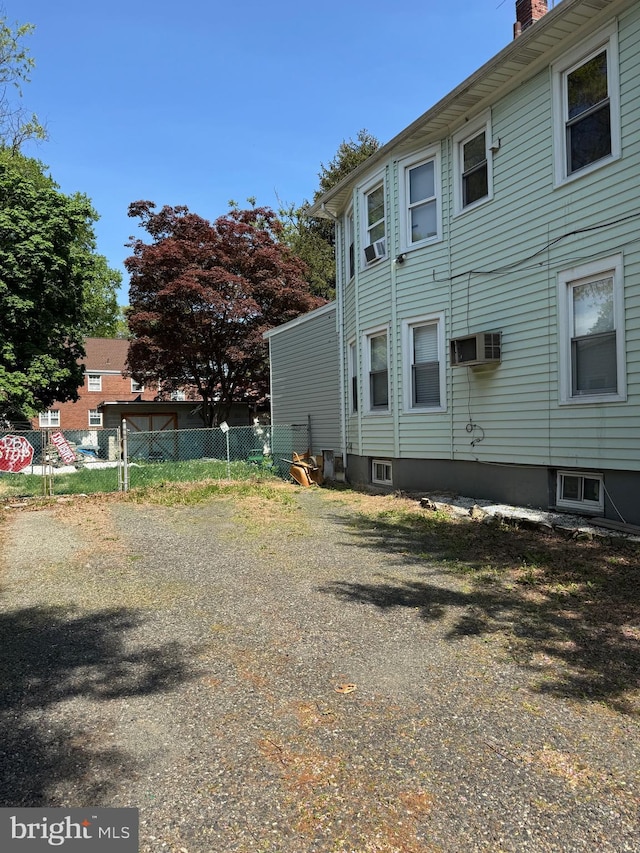 view of side of property featuring a wall mounted AC, fence, and a chimney