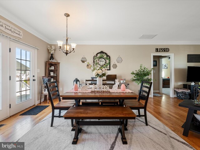 dining area featuring crown molding, visible vents, an inviting chandelier, and light wood-style floors