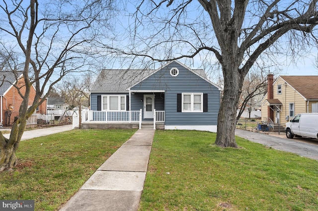 bungalow featuring covered porch and a front lawn