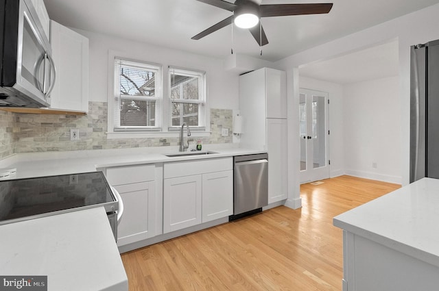 kitchen featuring stainless steel appliances, backsplash, a sink, a ceiling fan, and french doors