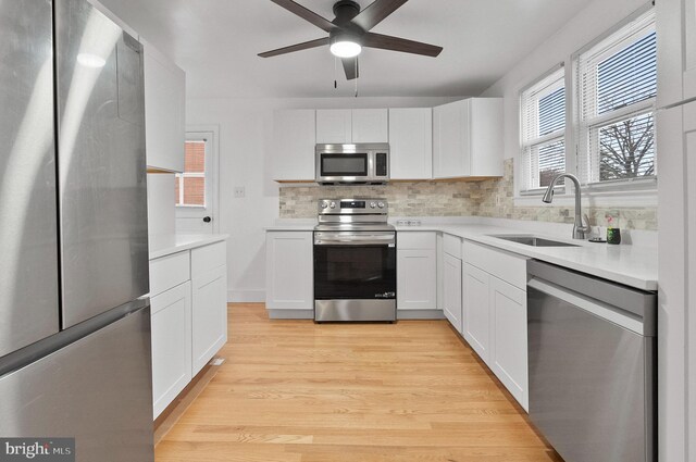 kitchen featuring a sink, stainless steel appliances, backsplash, light countertops, and white cabinets
