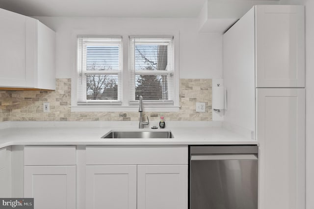 kitchen with decorative backsplash, light countertops, white cabinets, dishwasher, and a sink