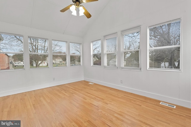 unfurnished sunroom with wood finished floors, a wooden deck, vaulted ceiling, baseboards, and visible vents