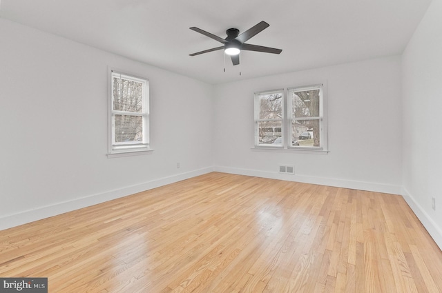 unfurnished room featuring baseboards, visible vents, wood finished floors, and a healthy amount of sunlight