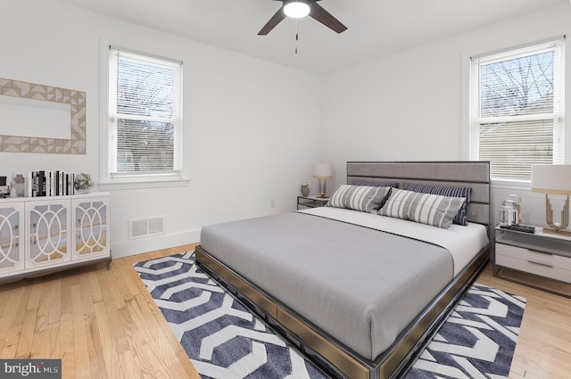 bedroom with baseboards, visible vents, wood finished floors, and a ceiling fan