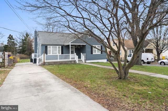 bungalow featuring a porch, a front lawn, driveway, and a shingled roof