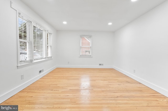 unfurnished room featuring wood finished floors, visible vents, a healthy amount of sunlight, and recessed lighting