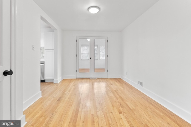 empty room with visible vents, light wood-style flooring, french doors, and baseboards