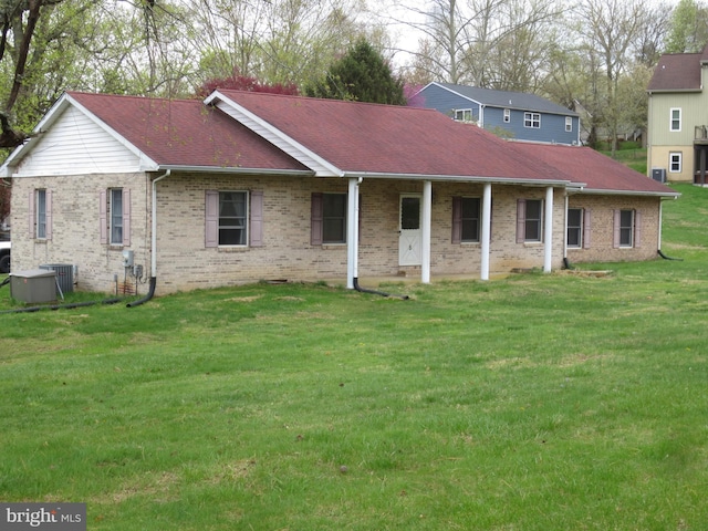view of front of property featuring central air condition unit, brick siding, a shingled roof, and a front yard