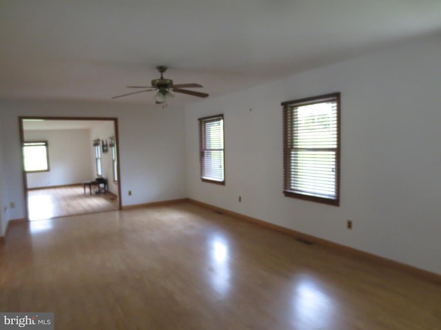 unfurnished room featuring a ceiling fan, baseboards, and light wood-style floors