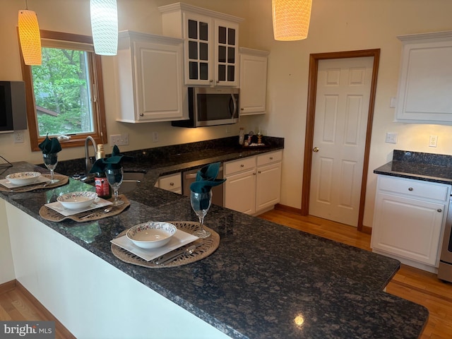 29 Salt Grass Rd, Ocean Pines, MD 21811 - kitchen featuring stainless steel microwave, light wood-type flooring, white cabinets, and dark stone counters