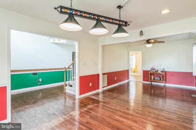 spare room with baseboards, wood finished floors, visible vents, and a ceiling fan