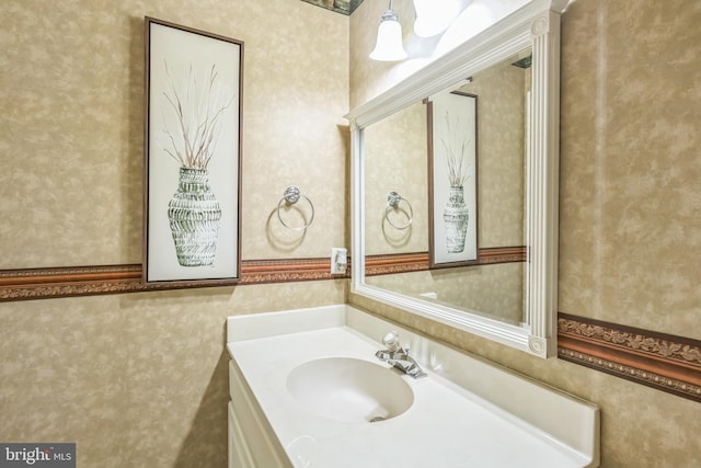 bathroom with wallpapered walls and vanity
