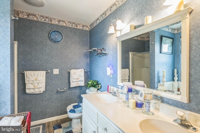 bathroom with wood finished floors, a sink, double vanity, and a stall shower