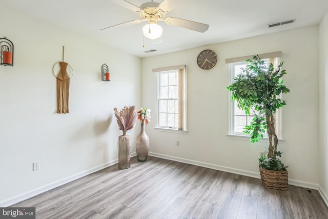 empty room featuring visible vents, baseboards, wood finished floors, and ceiling fan