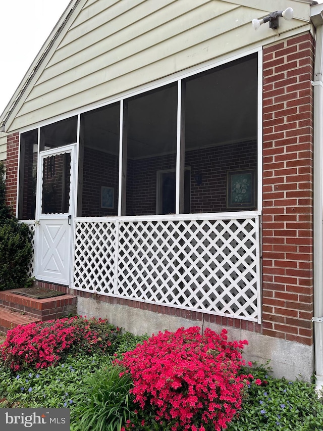 view of side of property with brick siding and a sunroom
