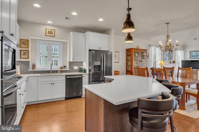 323 Valor Dr, Mechanicsburg, PA 17050 - kitchen with appliances with stainless steel finishes, tasteful backsplash, a sink, a notable chandelier, and light wood-style floors