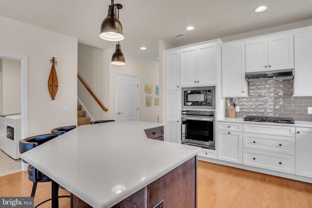 323 Valor Dr, Mechanicsburg, PA 17050 - kitchen featuring gas cooktop, black microwave, light countertops, under cabinet range hood, and oven