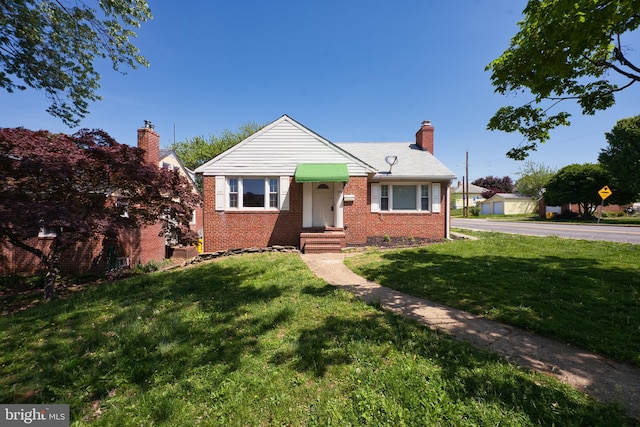 bungalow with a chimney, a front yard, and brick siding