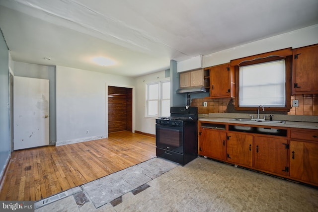 kitchen with a sink, decorative backsplash, black range with gas cooktop, and light countertops