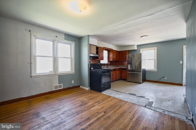 kitchen featuring high end fridge, light wood finished floors, baseboards, visible vents, and black gas range