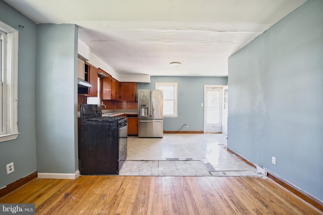 100 9th Ave, Baltimore, MD 21225 - kitchen featuring black range with gas cooktop, baseboards, stainless steel refrigerator with ice dispenser, and light wood-style floors