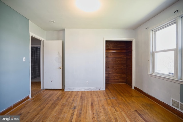 unfurnished bedroom featuring visible vents, baseboards, wood finished floors, and a closet