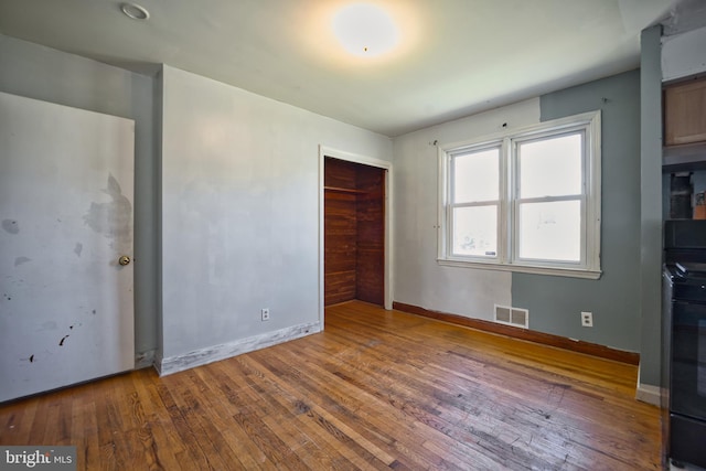 unfurnished bedroom featuring visible vents, wood-type flooring, baseboards, and a closet