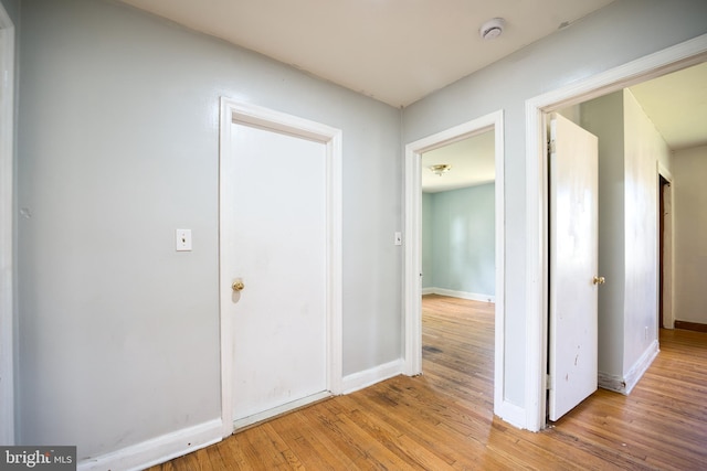 hallway featuring baseboards and light wood finished floors
