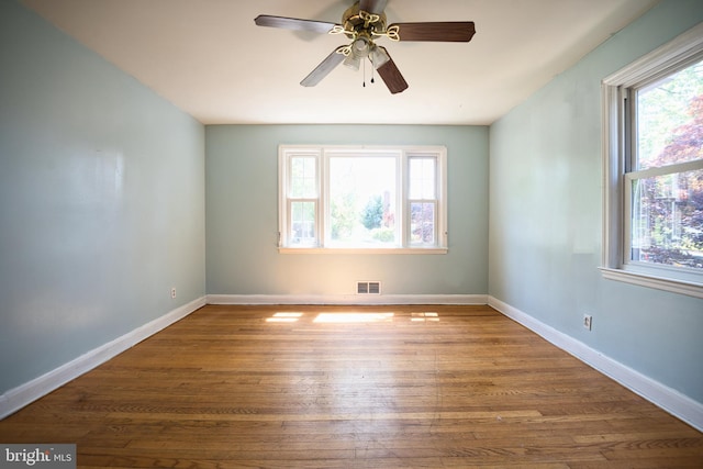 spare room with baseboards, visible vents, wood finished floors, and a wealth of natural light