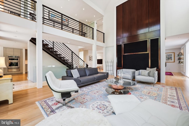 living room featuring wood finished floors, stairway, and a towering ceiling