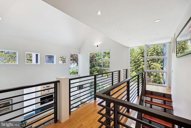 hall with recessed lighting, wood finished floors, vaulted ceiling, and an upstairs landing