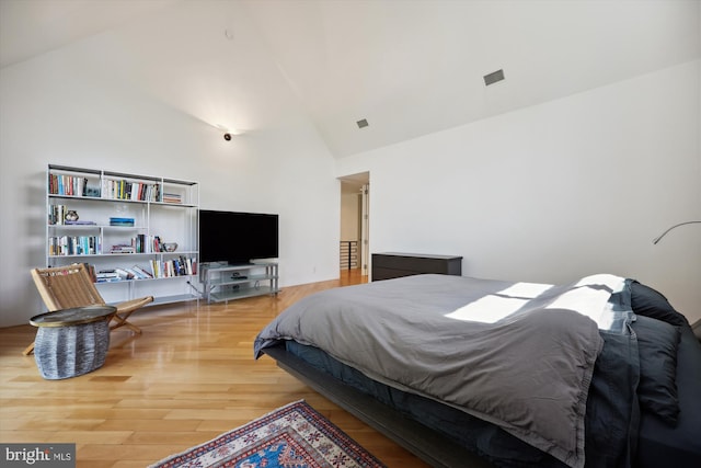 bedroom featuring visible vents, wood finished floors, and high vaulted ceiling