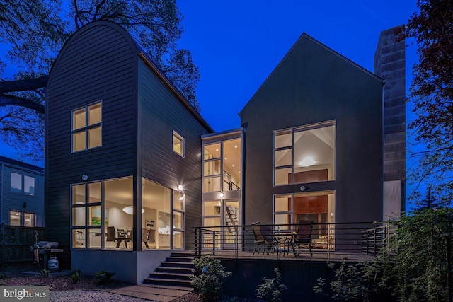 back of house at twilight featuring a chimney