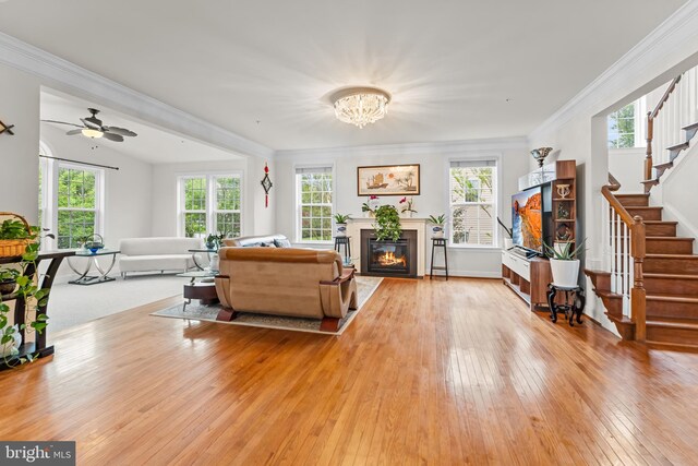 living area featuring healthy amount of natural light, hardwood / wood-style floors, stairway, and ornamental molding