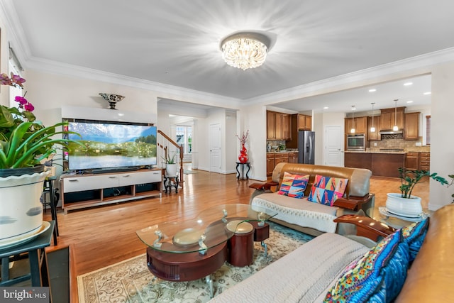 living room featuring a chandelier, light wood-type flooring, ornamental molding, stairs, and recessed lighting
