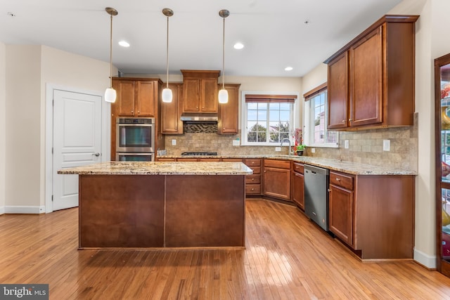 kitchen featuring stainless steel appliances, light wood finished floors, under cabinet range hood, decorative backsplash, and recessed lighting