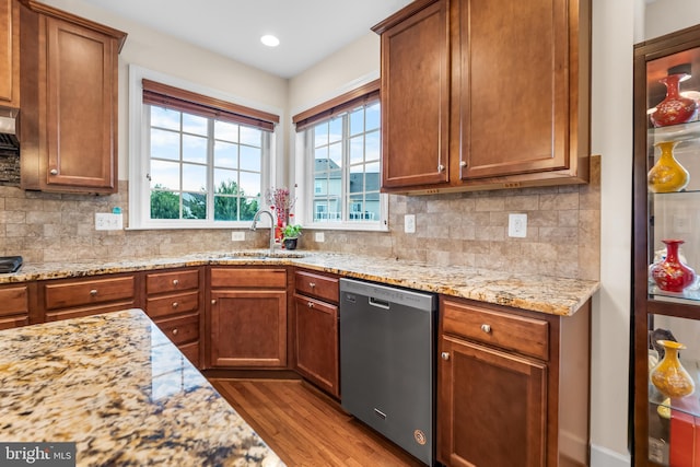 kitchen featuring dishwasher, a sink, wood finished floors, decorative backsplash, and recessed lighting