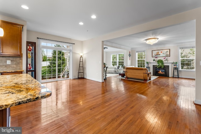 living area featuring light wood finished floors, a glass covered fireplace, baseboards, and recessed lighting