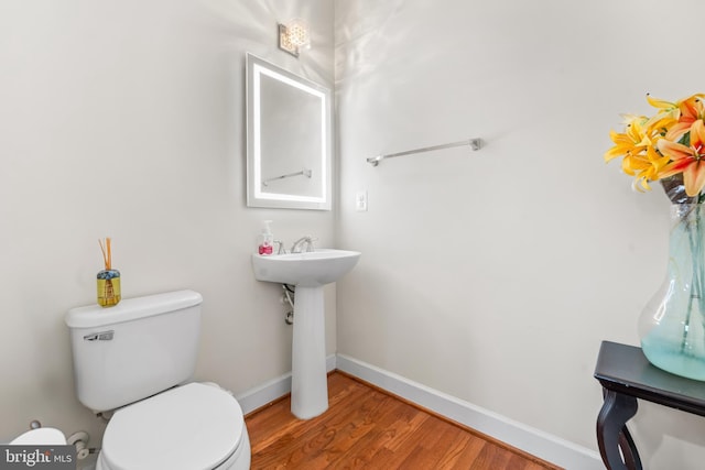 bathroom with wood finished floors, toilet, and baseboards