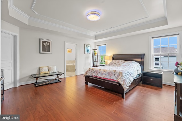 bedroom with a tray ceiling, wood finished floors, ornamental molding, and baseboards