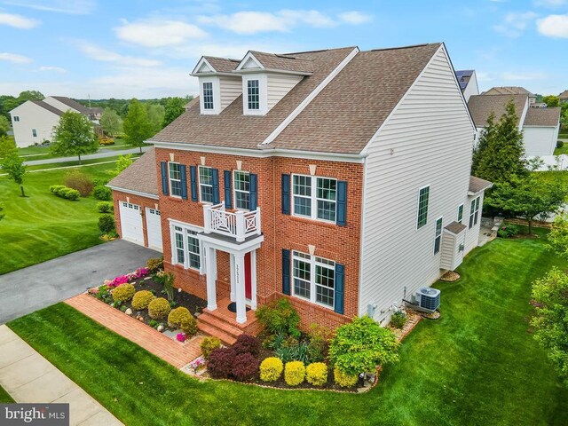 colonial inspired home featuring brick siding, central air condition unit, roof with shingles, and a front yard