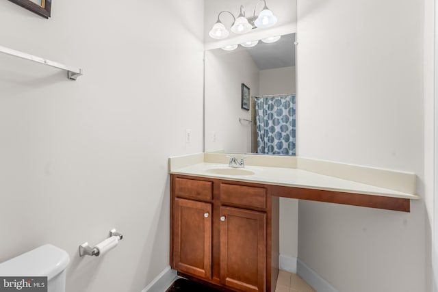 bathroom with vanity, toilet, baseboards, and tile patterned flooring