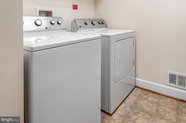 washroom featuring separate washer and dryer, light tile patterned flooring, and baseboards
